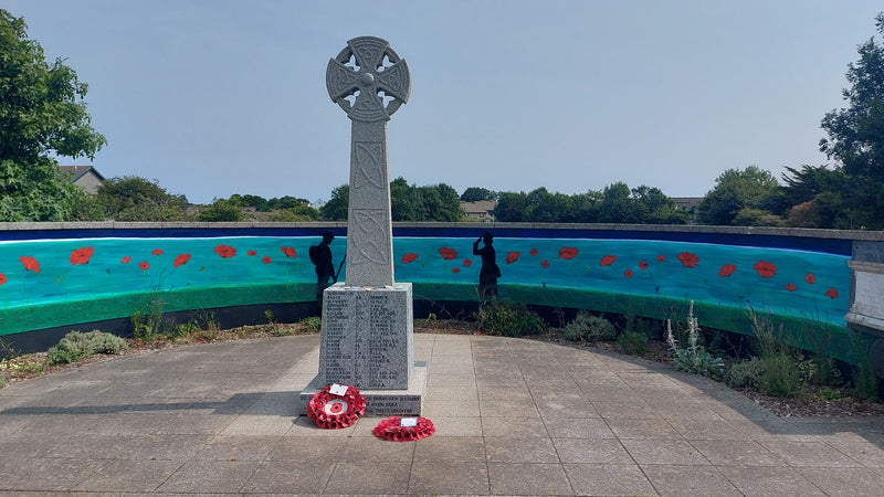 Memorial with wreaths in front, set against Annie B's mural.
