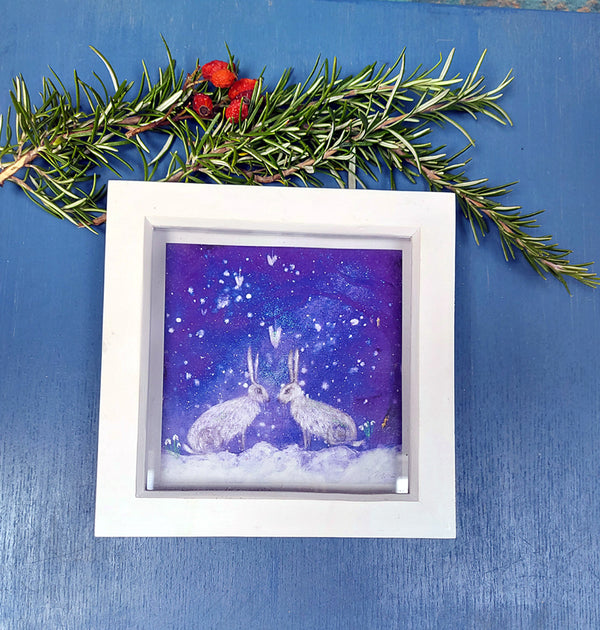 A mini print of my best selling  'hares under a snowy sky', hand finished ;with a touch of gold and sparkle in a white deep wooden frame ready for your walls. the perfect gift.  white hares, winter hares, hare and trees, hare art. rabbit art.  Annie b. art