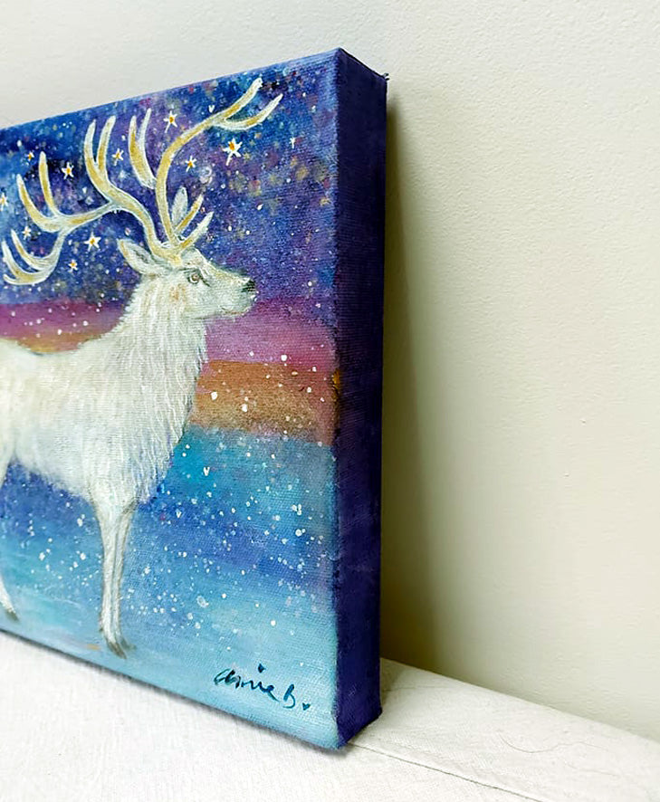 The majestic white stag stands proud surrounded by magic and stars under a snowy sky.   Mixed media on deep edge boxed canvas with a hint of gold and sparkle by visonary artist annie b.   Size 25cm x 25cm ready for your walls
