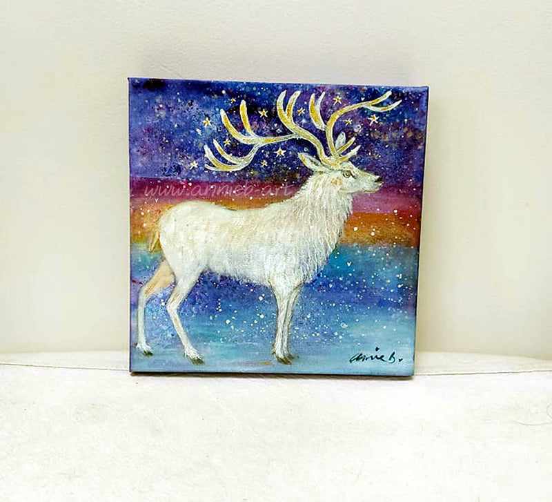 The majestic white stag stands proud surrounded by magic and stars under a snowy sky.   Mixed media on deep edge boxed canvas with a hint of gold and sparkle by visonary artist annie b.   Size 25cm x 25cm ready for your walls