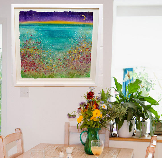Cornish wild flowers dance happily above a Cornish cove under a new moon.  A large mixed medium painting on hand made paper, mounted and framed with a white washed wooden frame ready for your walls to uplift any space.